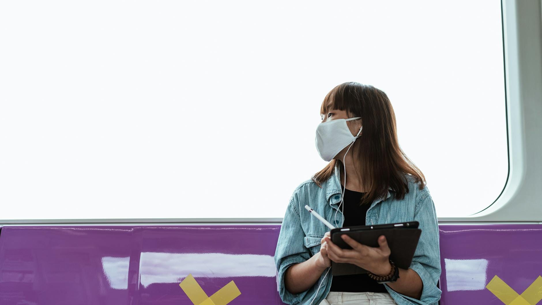 Kobieta w maseczce korzysta z tabletu w pociągu podczas pandemii